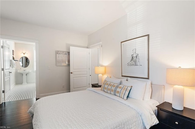 bedroom with connected bathroom, a sink, baseboards, and wood finished floors