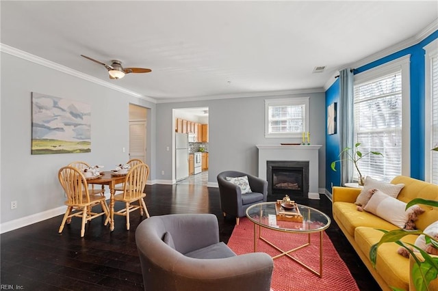 living area featuring baseboards, a glass covered fireplace, hardwood / wood-style flooring, and crown molding