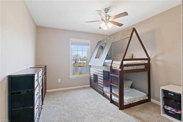 carpeted bedroom featuring a textured ceiling, baseboards, and a ceiling fan