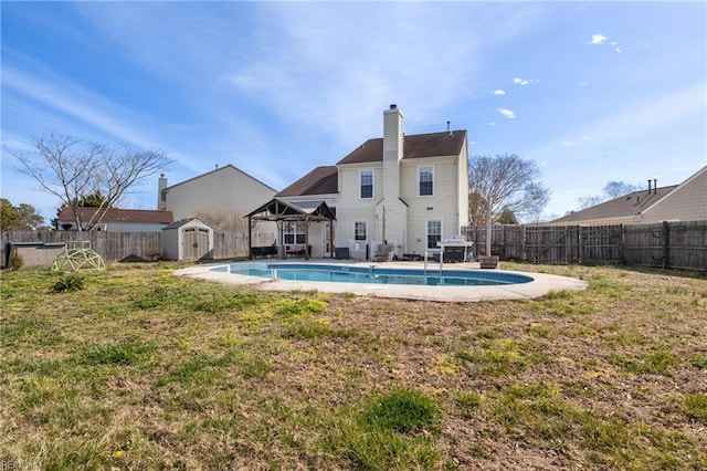 back of property with a fenced in pool, an outbuilding, a fenced backyard, and a shed