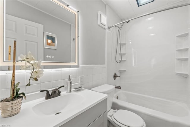 bathroom featuring toilet, vanity, tile walls, and shower / bathtub combination