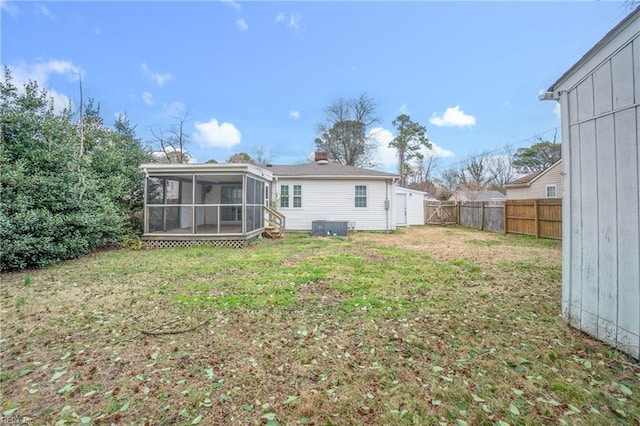 rear view of property featuring a sunroom, a fenced backyard, central AC, and a lawn