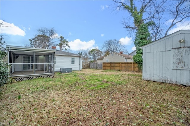 view of yard featuring a sunroom, a fenced backyard, a storage shed, and an outdoor structure