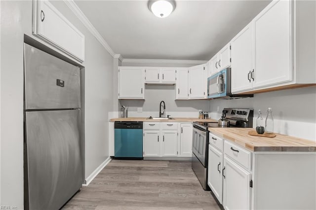 kitchen featuring stainless steel appliances, crown molding, white cabinetry, wooden counters, and a sink