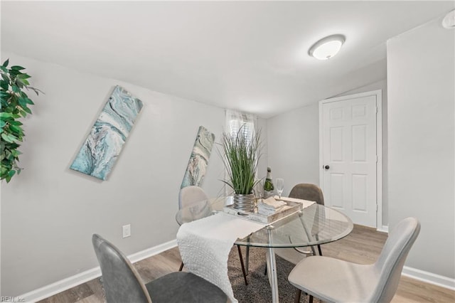 dining room featuring lofted ceiling, baseboards, and wood finished floors