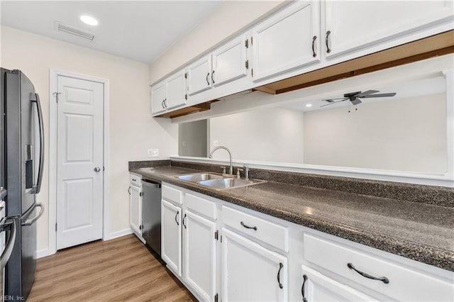 kitchen with appliances with stainless steel finishes, white cabinets, a sink, and visible vents