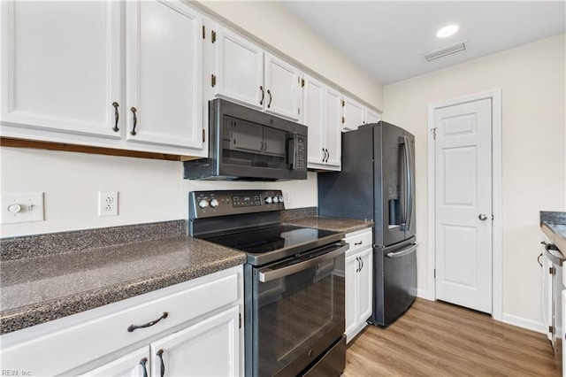 kitchen featuring dark countertops, visible vents, light wood-style floors, white cabinets, and black appliances