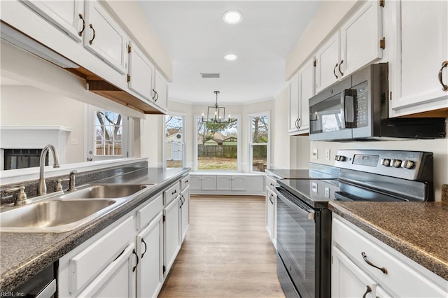 kitchen featuring electric range, visible vents, white cabinets, and a sink