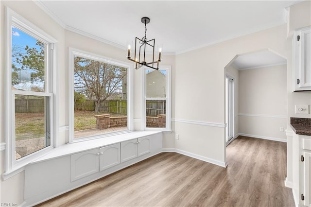 unfurnished dining area featuring crown molding, baseboards, a chandelier, and light wood-style floors