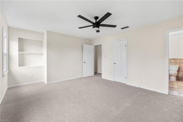 unfurnished bedroom with carpet floors, visible vents, baseboards, and ensuite bathroom