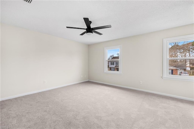 empty room featuring a ceiling fan, carpet, a textured ceiling, and baseboards