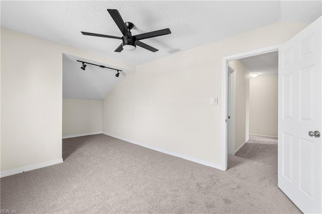 additional living space featuring a textured ceiling, carpet floors, vaulted ceiling, and baseboards