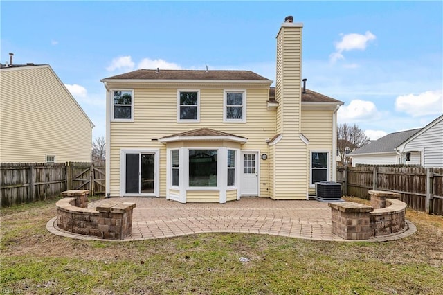 rear view of property featuring a patio, a chimney, and a fenced backyard