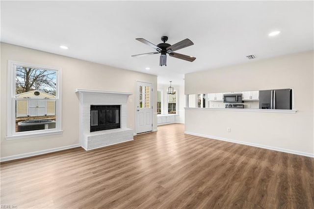 unfurnished living room featuring a fireplace, recessed lighting, visible vents, ceiling fan, and wood finished floors