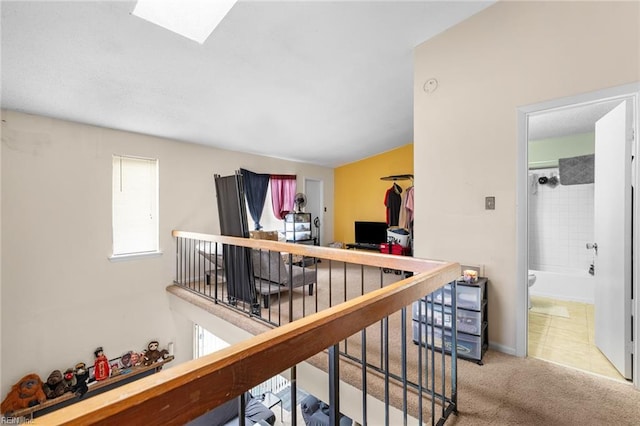 hall featuring a skylight, carpet, and an upstairs landing