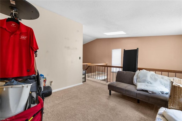 interior space with a textured ceiling, vaulted ceiling with skylight, carpet flooring, and baseboards