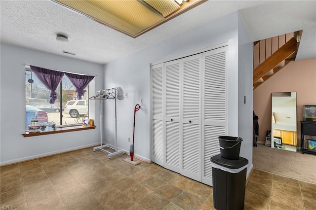 interior space with a closet, visible vents, a textured ceiling, and baseboards