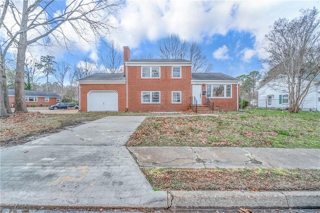 tri-level home with a garage, driveway, brick siding, and a chimney