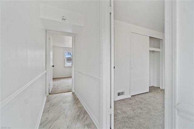 hall with baseboards, marble finish floor, visible vents, and light colored carpet