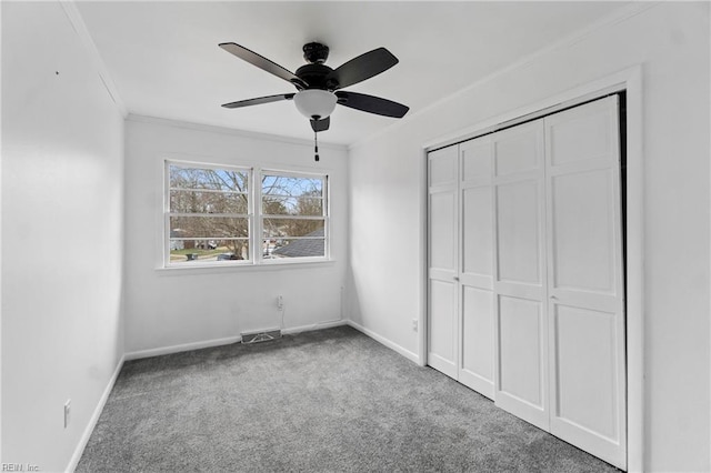 unfurnished bedroom featuring carpet, a closet, ornamental molding, and baseboards