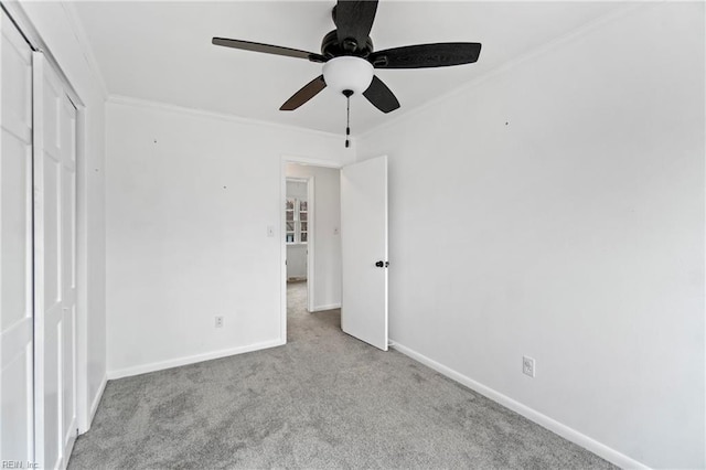 unfurnished bedroom with carpet flooring, a ceiling fan, baseboards, a closet, and crown molding