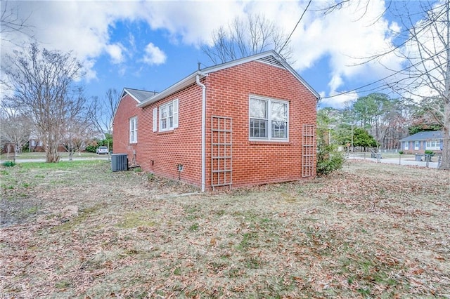 view of side of property featuring crawl space, cooling unit, and brick siding