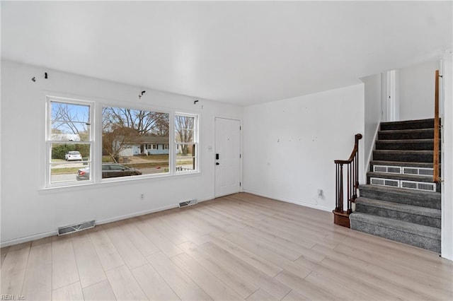 unfurnished living room featuring visible vents, stairway, baseboards, and wood finished floors