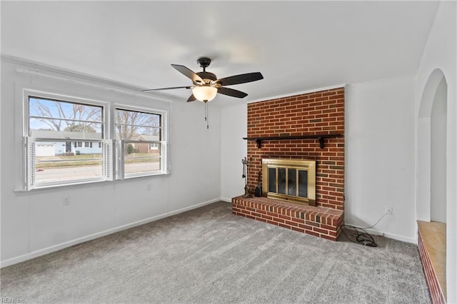 unfurnished living room featuring ceiling fan, arched walkways, a fireplace, carpet flooring, and baseboards