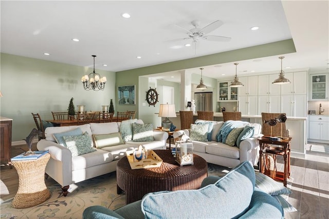 living room featuring ceiling fan with notable chandelier, recessed lighting, and wood finished floors