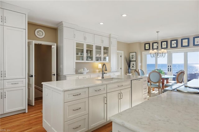 kitchen featuring light wood-style flooring, paneled dishwasher, ornamental molding, white cabinets, and a sink