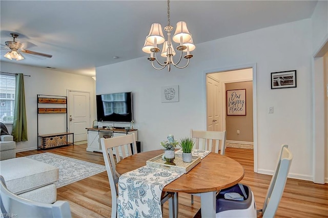 dining area with light wood-style flooring, baseboards, and ceiling fan with notable chandelier