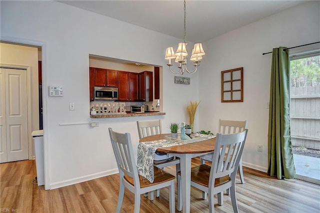 dining area featuring a chandelier, light wood-type flooring, and baseboards