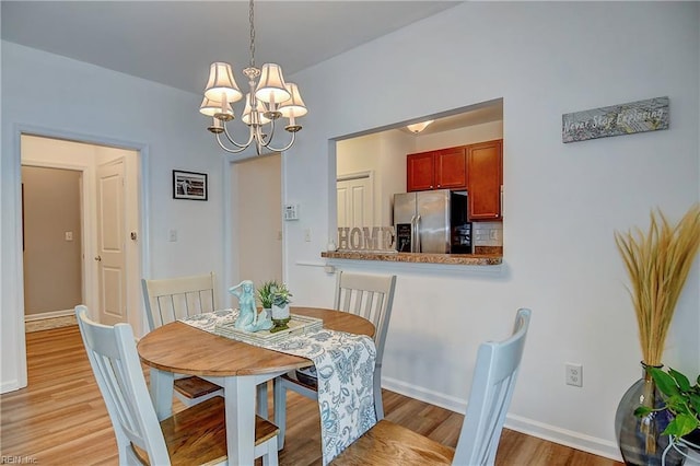 dining space with light wood-style flooring, baseboards, and a notable chandelier