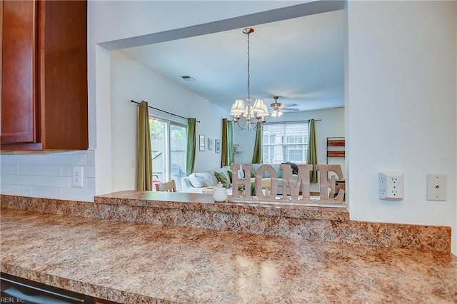 interior space featuring brown cabinets, a notable chandelier, decorative light fixtures, visible vents, and decorative backsplash