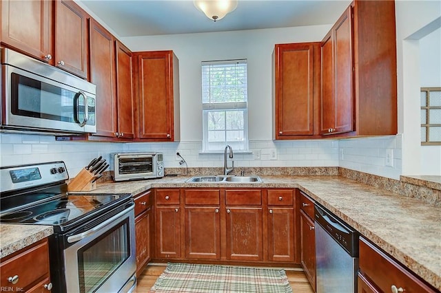 kitchen with appliances with stainless steel finishes, decorative backsplash, a sink, and a toaster