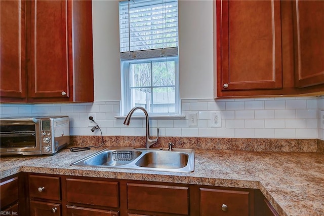 kitchen with light countertops, tasteful backsplash, a sink, and a toaster