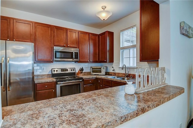 kitchen featuring a toaster, appliances with stainless steel finishes, a sink, light countertops, and backsplash