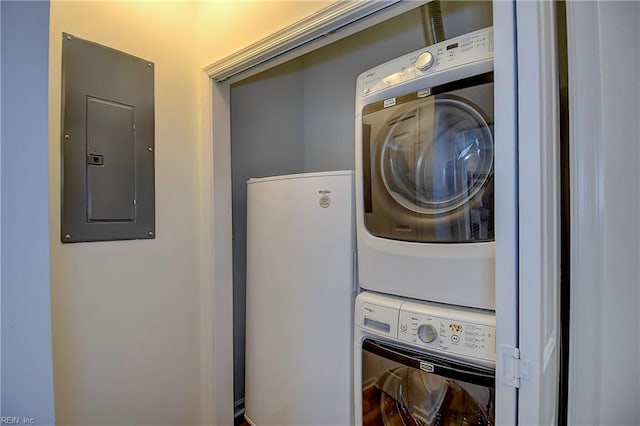 laundry room with stacked washer and dryer, electric panel, and laundry area