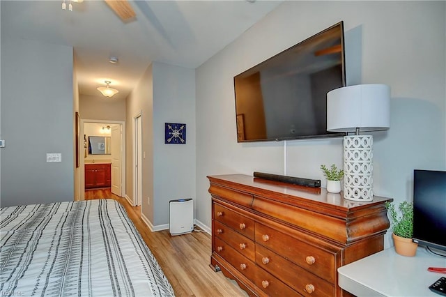 bedroom featuring connected bathroom, light wood-style flooring, and baseboards