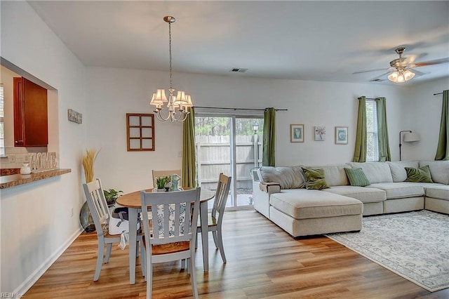 dining space featuring visible vents, ceiling fan with notable chandelier, light wood-style flooring, and baseboards