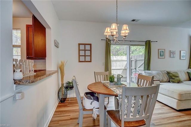 dining room featuring a chandelier, light wood-type flooring, baseboards, and a healthy amount of sunlight