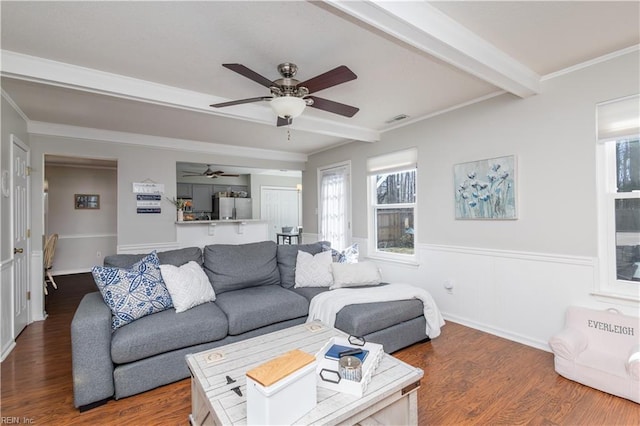 living area with ornamental molding, beam ceiling, wood finished floors, and visible vents