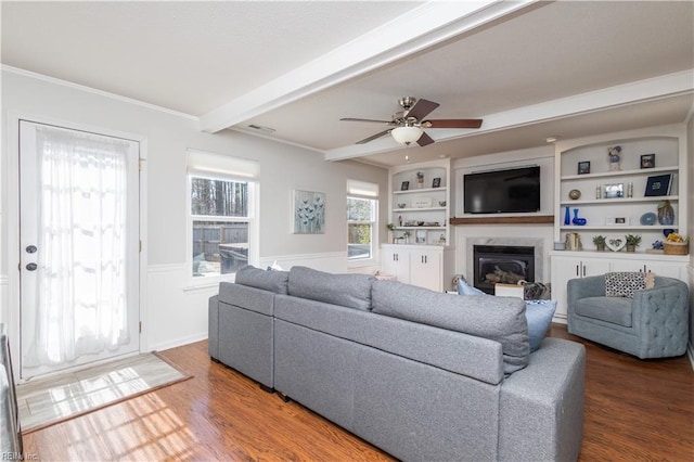 living room featuring a premium fireplace, wood finished floors, visible vents, built in features, and beamed ceiling