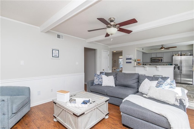 living room with beam ceiling, crown molding, visible vents, light wood-type flooring, and baseboards