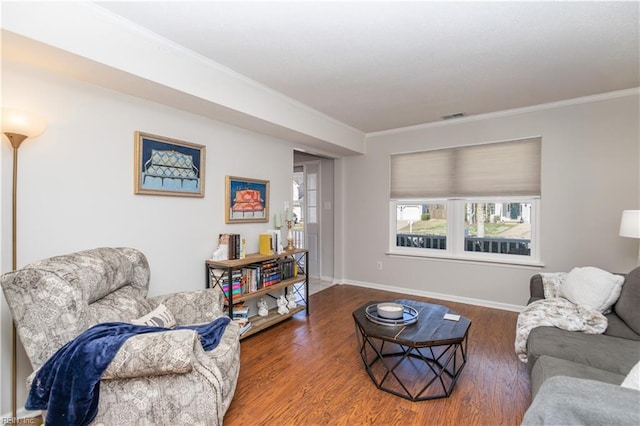 living room featuring baseboards, crown molding, visible vents, and wood finished floors