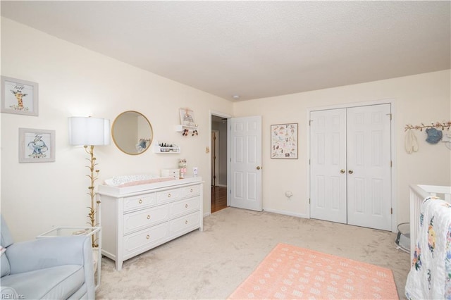 bedroom featuring light carpet, a textured ceiling, baseboards, and a closet