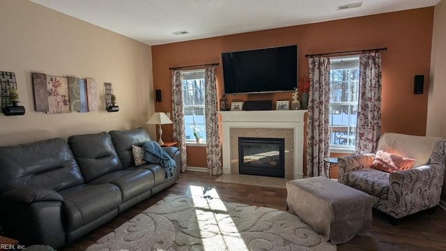 living area with a fireplace with flush hearth, visible vents, a wealth of natural light, and wood finished floors