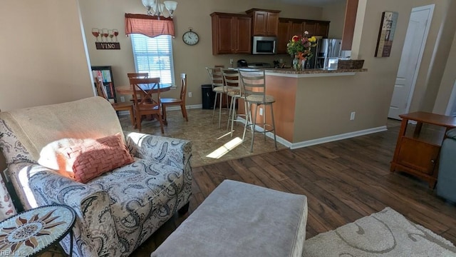 kitchen with baseboards, a breakfast bar, wood finished floors, an inviting chandelier, and stainless steel appliances