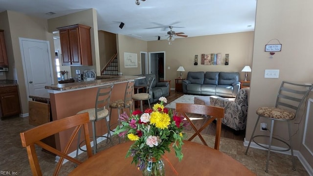 living room featuring a ceiling fan, baseboards, and stairs