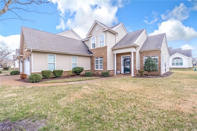 traditional-style home with an attached garage, a shingled roof, a front lawn, and brick siding